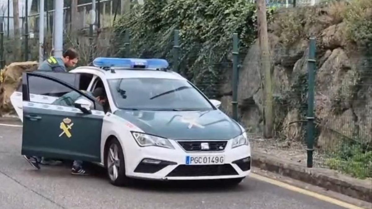Los agentes de la Guardia Civil de Asturias introducen al detenido en el vehículo policial.