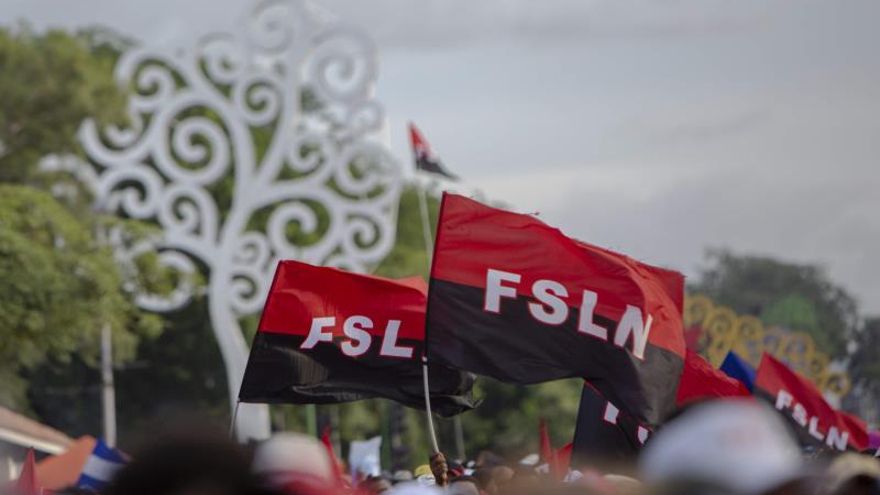 En la imagen, una caminata con personas portando banderas del partido FSLN.