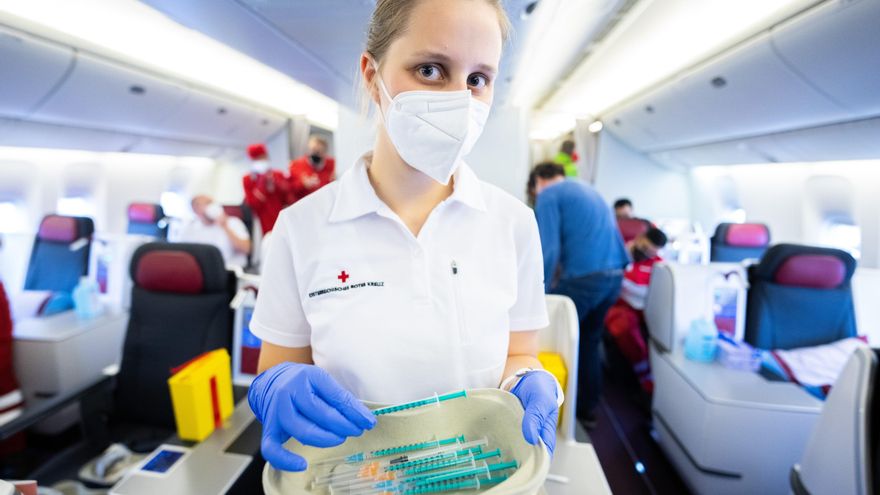 Una trabajadora sanitaria prepara dosis de refuerzo dentro de un avión Boeing 777 en el aeropuerto de Viena.