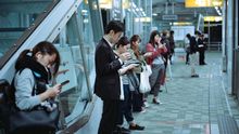 Personas mirando sus móviles en un andén de metro.