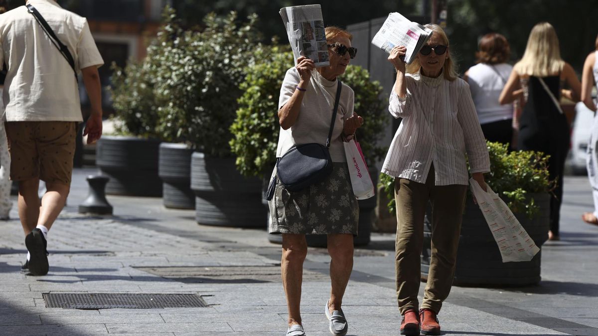 Viandantes se protegen del sol mientras camina por una calle de Toledo, este jueves.