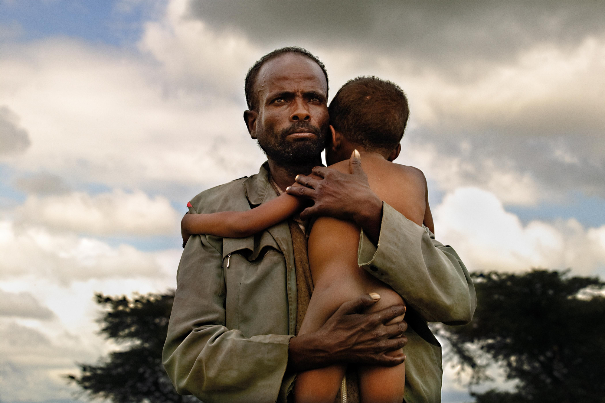 Era una emergencia nutricional en una zona de Etiopía donde la desnutrición ya es endémica. La sequía y las plagas de langostas habían vuelto a dejar baldíos todos los terrenos de la región, y las cosechas habían dejado de serlo. No llovía y, si lo hacía, quedaba todo anegado. Numerosas madres se arremolinaban a las puertas del centro nutricional, pero la imagen apareció de repente. Un padre llevaba a su hijo en brazos. Me sorprendió. No era lo habitual, aunque lo más llamativo era su mirada. Se llamaba Abebaye y el niño, Basada Moti. Volví a la región al cabo de un tiempo y los visité en su aldea. (Oromía, Etiopía, 2008).