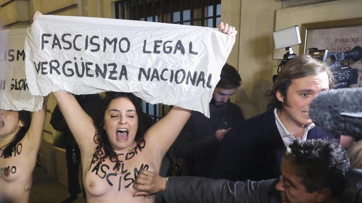 Un hombre toca el pecho a una de los dos activistas de Femen que protestan con motivo de la misa organizada en recuerdo al dictador, este jueves en la parroquia de los Doce Apóstoles, en la calle Velázquez en Madrid.