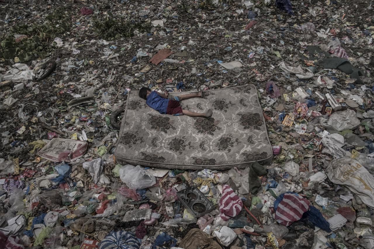 'Living Among What's Left Behind', tercer premio de la categoría 'Medio ambiente'. Un niño que recolecta material reciclable tumbado en un colchón rodeado de basura que flota en el río Pasig, en Manila (Filipinas)
