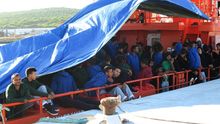 Varios migrantes amanecen tras pasar la noche en la cubiertos del Concepción Arenal bajo una lona de plástico.