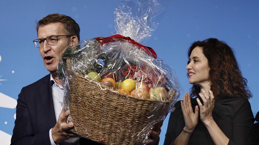 El líder del PP, Alberto Núñez Feijóo, esgrime una cesta de fruta junto a la presidenta de Madrid, Isabel Díaz Ayuso, en un acto navideño del partido en 2023, después del "hijo de puta" que espetó en la investidura de Pedro Sánchez.
