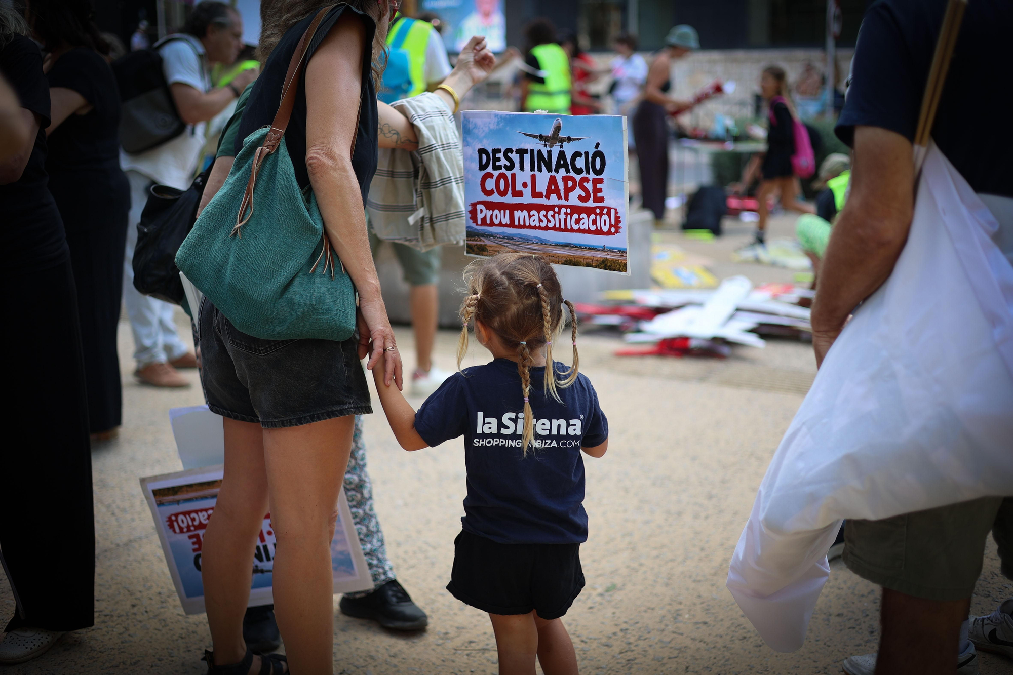 Una nena porta un cartell amb el missatge 'Destinació: col·lapse. Prou massificació!'