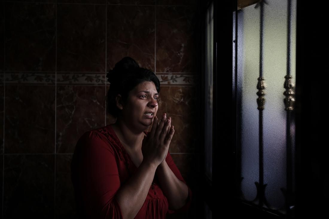 Raquel reza y llora en la entrada de la casa donde vive con su familia (su marido José y sus cinco hijos) durante su desahucio el 19 de mayo.  | OLMO CALVO