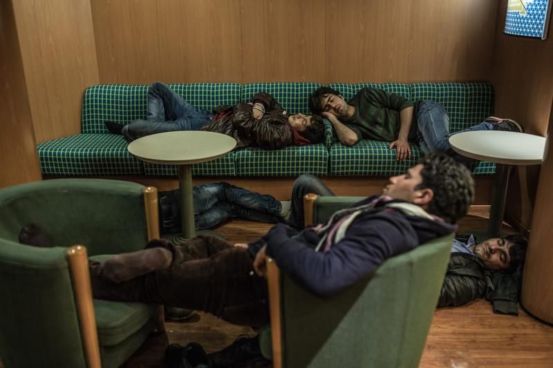 Un grupo de afganos duerme en los sofás del ferry que va de Lesbos a Atenas. Las personas refugiadas y migrantes que llegan a Lesbos cogen este ferry y al llegar a Atenas suben hasta Idomeni, donde cruzan la frontera entre Grecia y Macedonia. En el ferry se mezclan las personas que buscan refugio con los turistas o con habitantes griegos. © Pablo Tosco/Oxfam Intermón