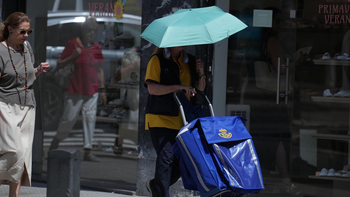 Una trabajadora de Correos se protege del sol con un paraguas en las calles de Bilbao.