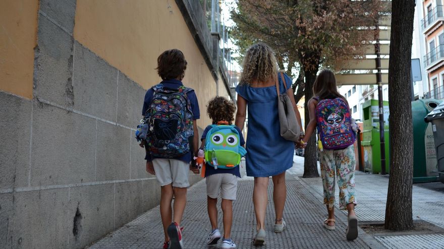 Una mujer lleva a varios niños al colegio.