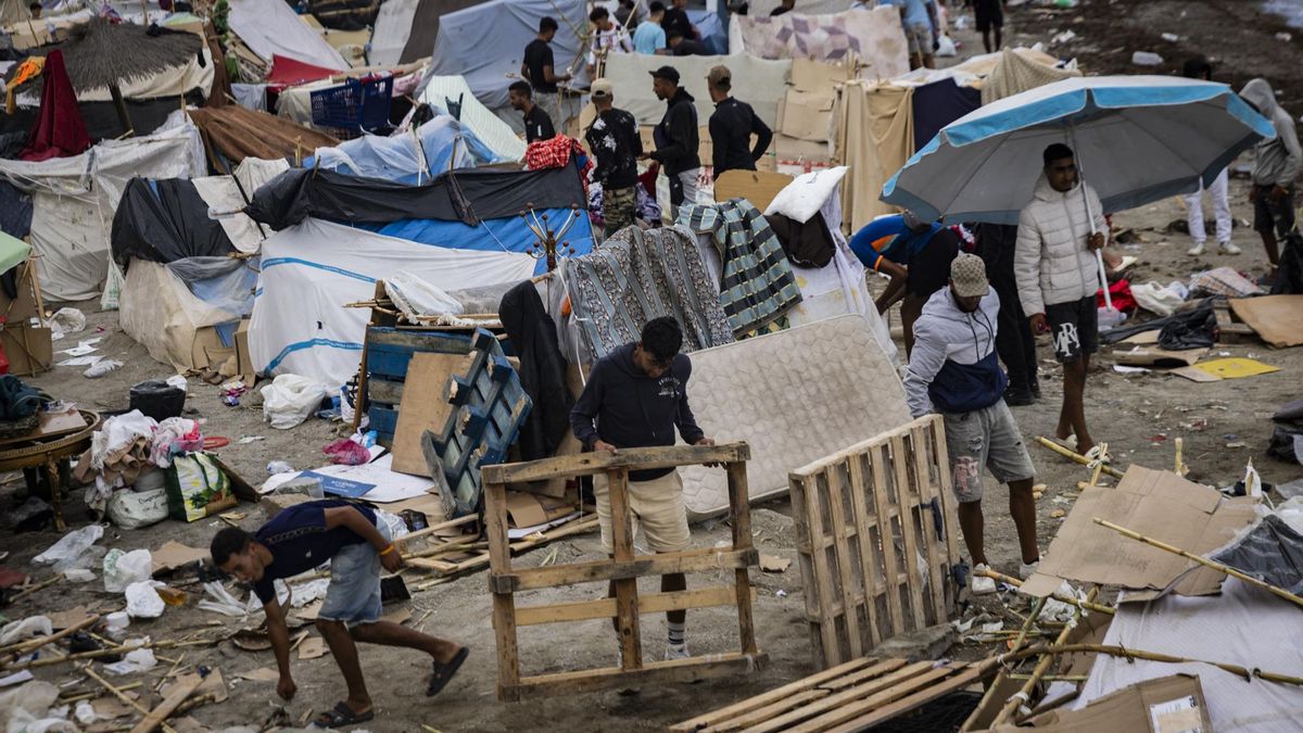 Migrantes recogiendo trozos de madera en la playa ceutí de El Trampolín.