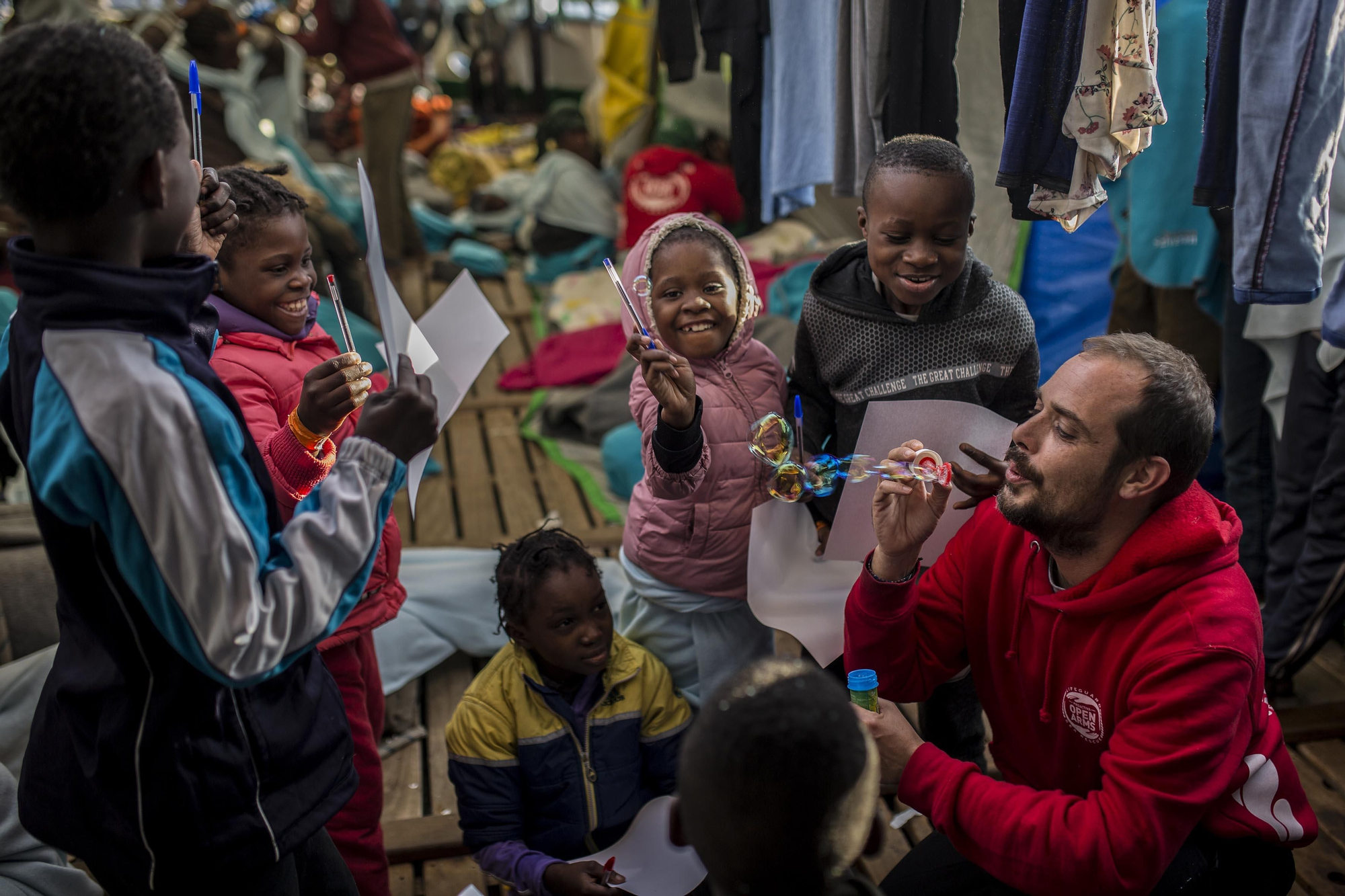 Marc, capitán del Open Arms durante la misión 57 de la ONG, hace pompas de jabón para distraer a algunos de los niños rescatados / Olmo Calvo