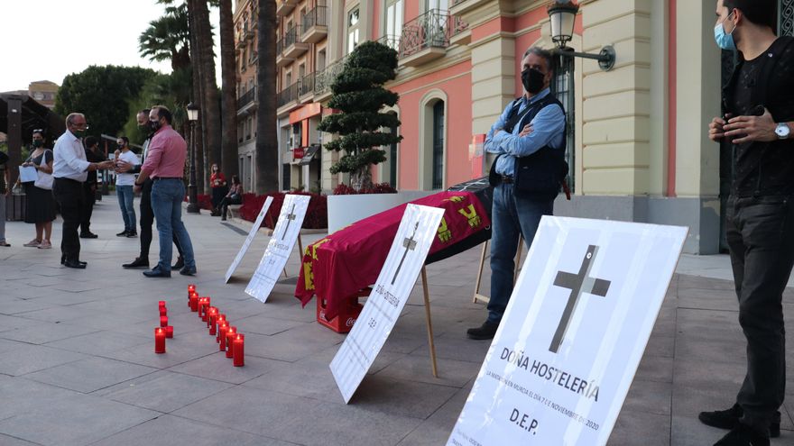 Un ataúd y carteles que anuncian el cierre y la muerte de la hostelería, en Murcia