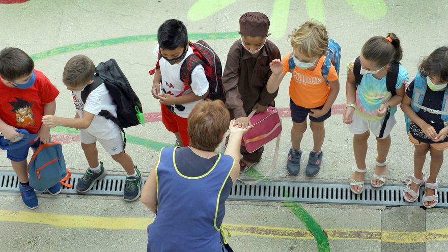 Varios niños y niñas saludan a su maestra en el primer día de clase en el colegio Balmes de València.