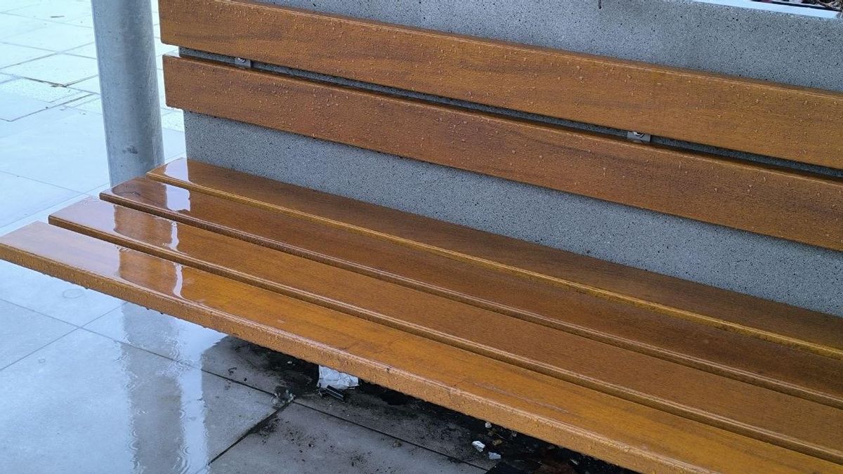 Los bancos bajo la pérgola bioclimática durante un día de lluvia.