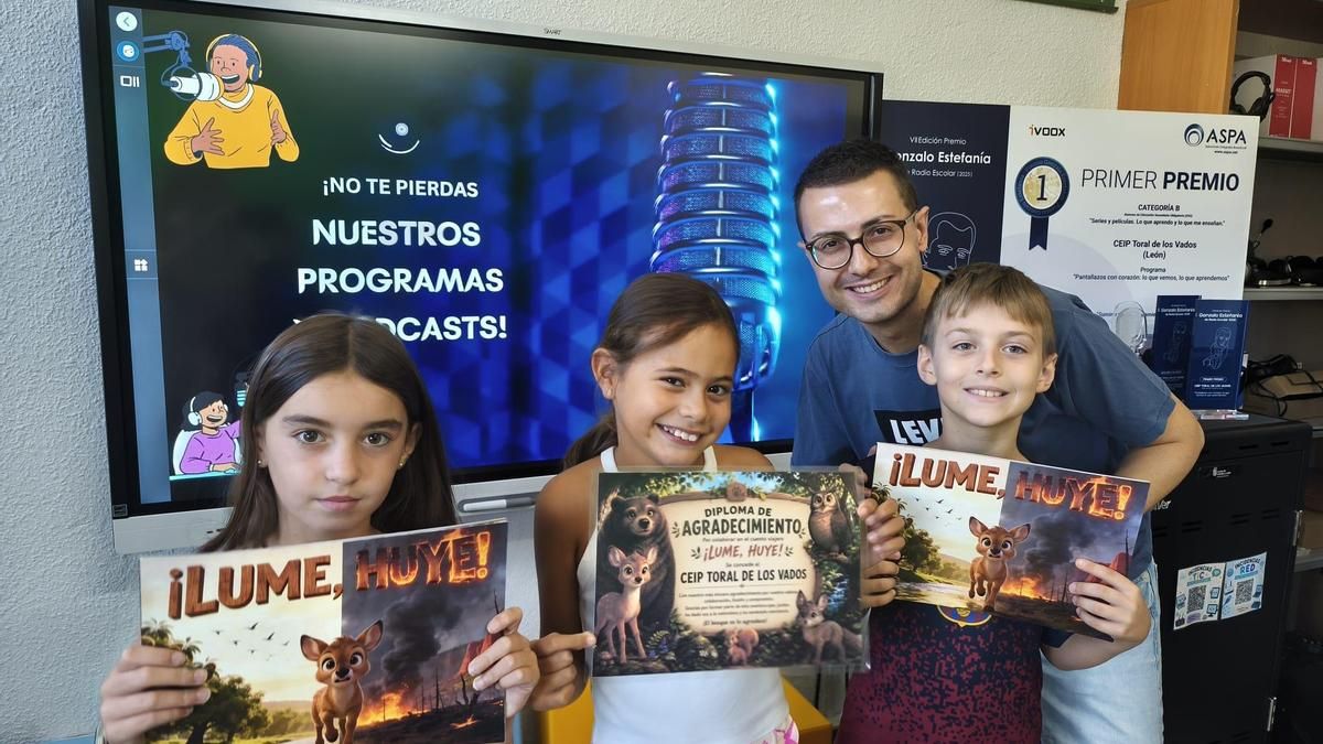 Adrián Barba Morán, coordinador de la radio escolar Menudo Toral del Colegio de Educación Infantil y Primaria Toral de los Vados, con varios alumnos del centro posando con el libro basado en el pódcast 'Lume, huye'. 