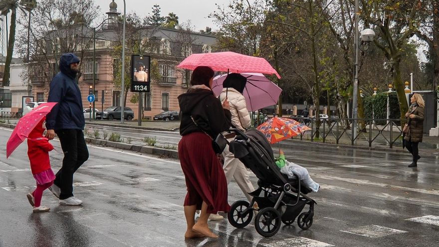 Padres con niños pasean por la calle en Sevilla en un día con clases presenciales suspendidas por la borrasca Leonardo.