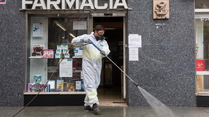 Un trabajador municipal desinfecta los alrededores de una Farmacia.