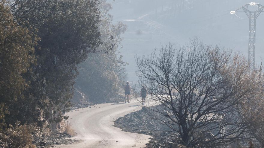 Unas vecinas pasean por las montañas que rodean la Vilavella (Castellón), cuando el incendio declarado el pasado sábado en el término municipal de la Vall d'Uixó (Castellón).