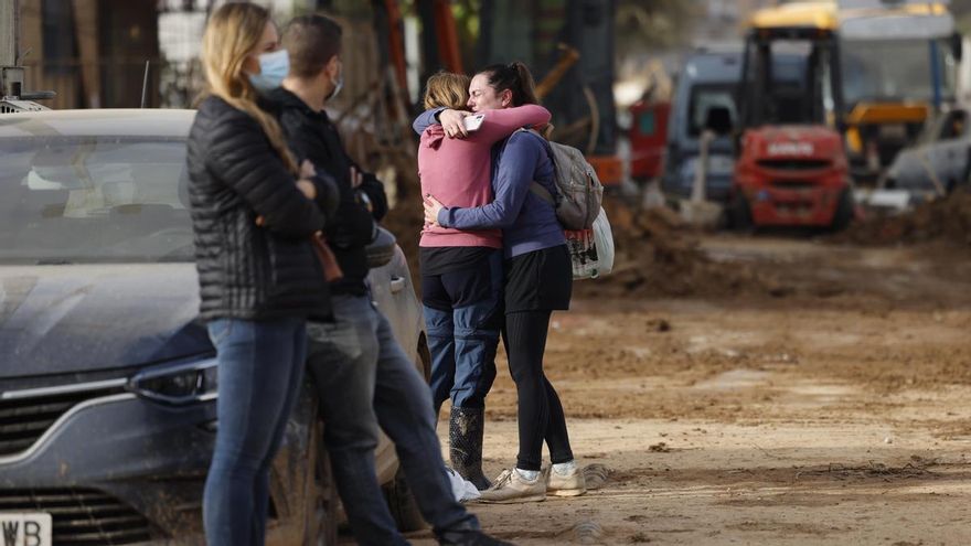 Dos mujeres se abrazan este domingo en una calle de Paiporta, donde siguen las labores de limpieza y reconstrucción de la localidad tras el paso de la DANA