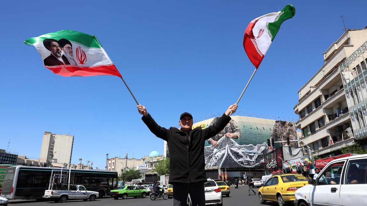Un hombre ondea banderas iraníes en la plaza de Enghelab de Teherán, el 22 de abril de 2026.