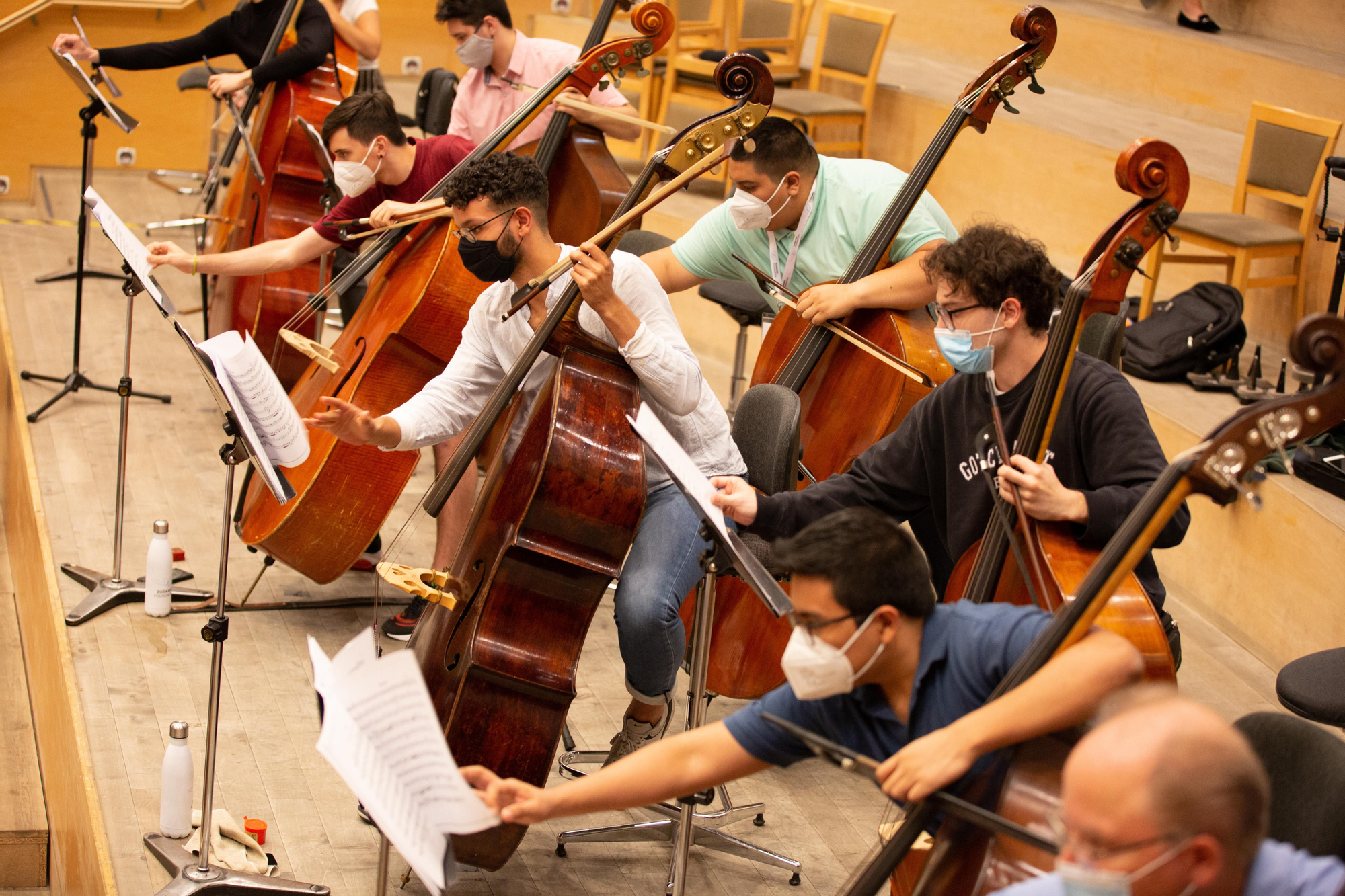 Un grupo de músicos coordinados al pasar la página de la partitura durante el ensayo dirigido por Dudamel