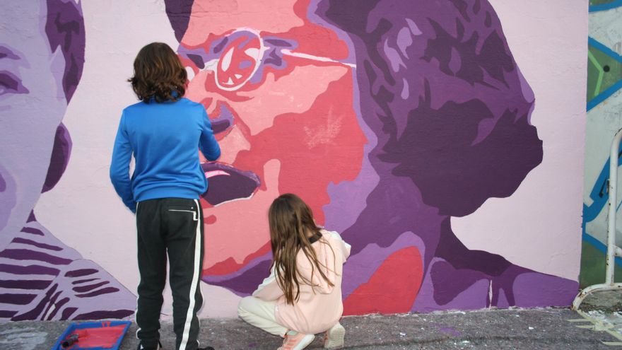 Un niño y una niña contribuyen al pintado del rostro de la anarquista Federica Montseny