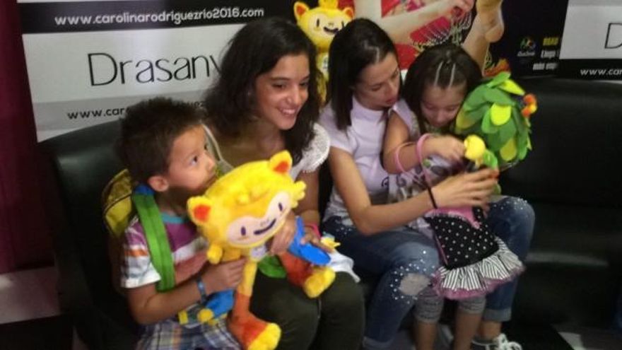 Carol (d) junto a Sara Llana (i) y una pareja de niños, disfrutando de las mascotas de los Juegos Olímpicos.
