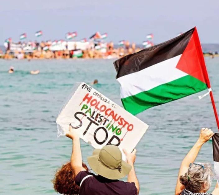 Decenas de personas han participado este domingo 24 de agosto en una protesta bajo el lema Mójate por Gaza,  en la playa de Las Canteras, en Las Palmas de Gran Canaria, para exigir el fin del genocidio en Palestina.
