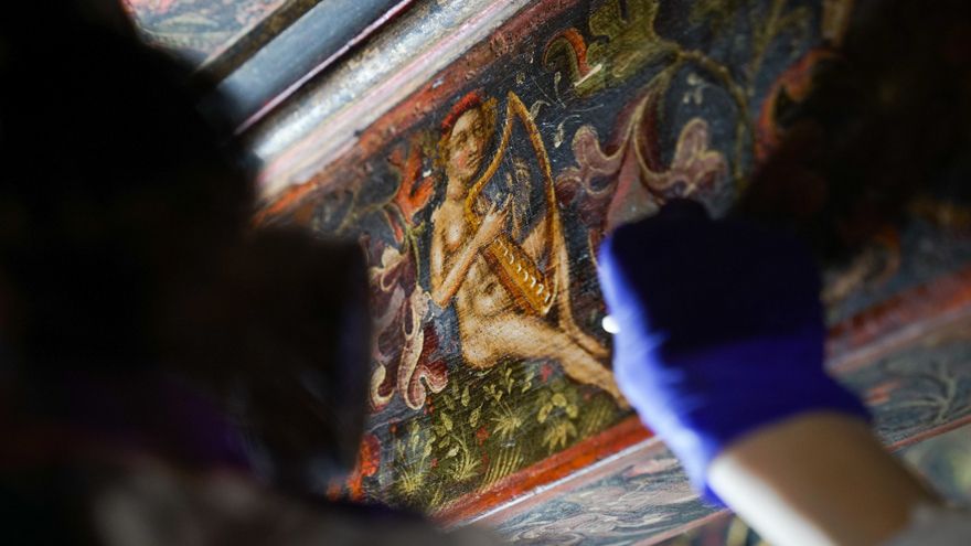 Una restauradora limpia una viga decorada con pintura renacentista