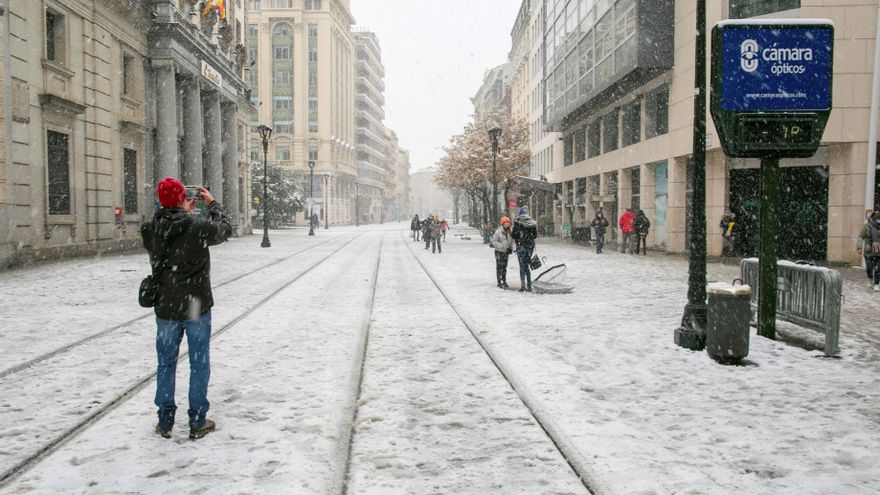 Un joven fotografía una avenida de Zaragoza, cubierta de nieve este sábado. EFE/ Javier Cebollada