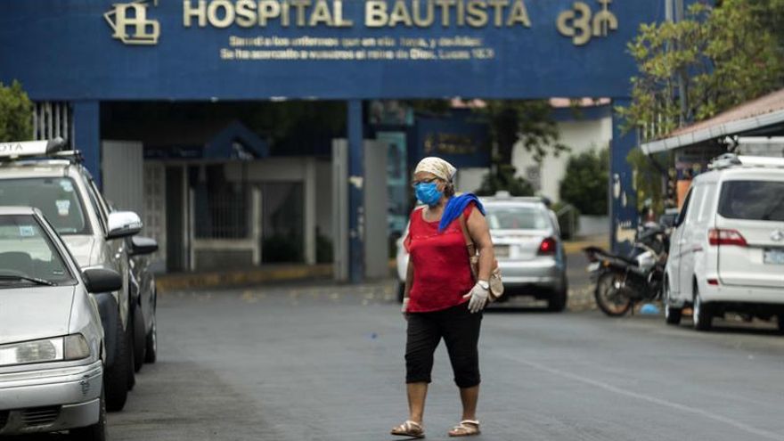 Una mujer con tapabocas y guantes es vista mientras cruza la calle frente a un hospital privado hoy jueves en Managua (Nicaragua).