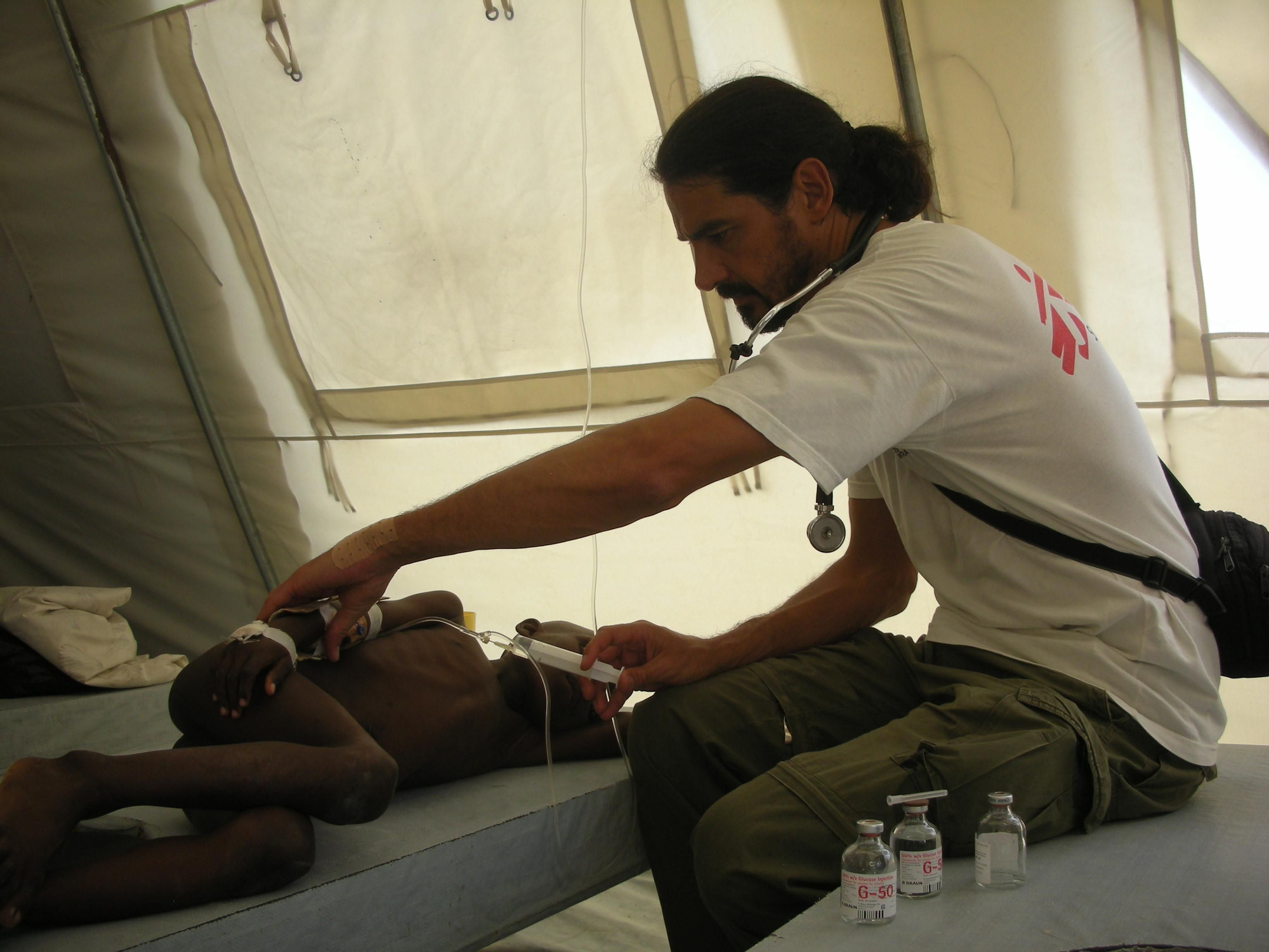 18 de diciembre de 2010. Desde que la epidemia de cólera diera comienzo, la enfermedad se ha cobrado más de 7.500 vidas y ha alcanzado alrededor de 600.000 casos conocidos (aproximadamente el 6% de la población del país). Sergio Cabral, pediatra, atiende a un chico en el centro de tratamiento de cólera de Sarthe. Fotografía: Aurelie Baumel