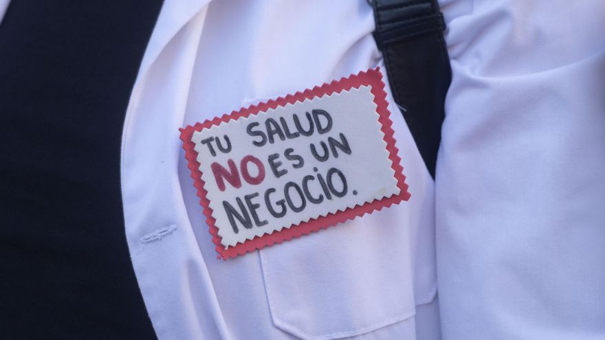 Un hombre con un pin en el que se lee: 'Tu salud no es un negocio'.
