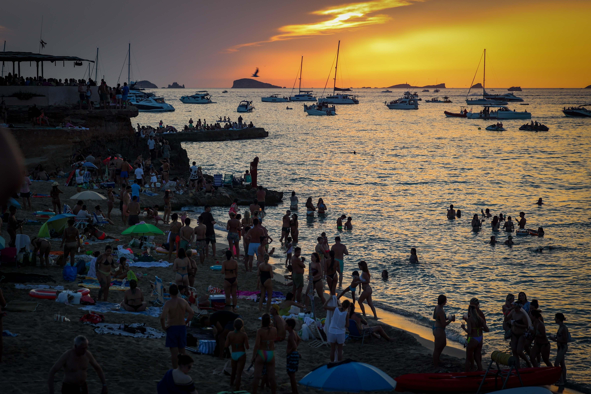 Miles de personas abarrotan la arena, los acantilados y las aguas de Cala Comte para coger sitio en el que ya es el evento astronómico más icónico de la historia reciente de la isla