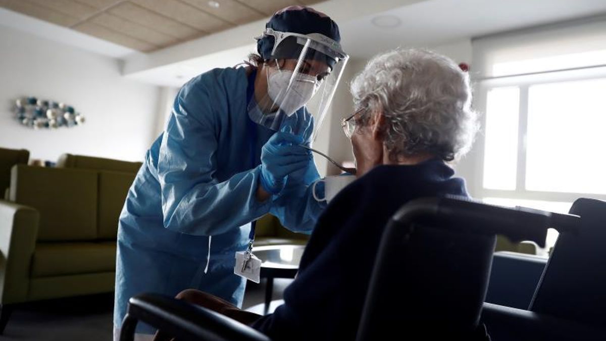 Anciana recibe comida de una trabajadora de una residencia durante la pandemia. | Archivo