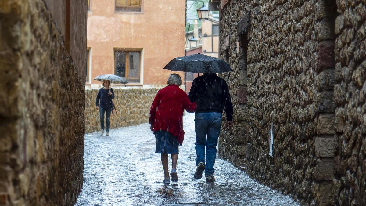 Varias personas caminan por una calle de Albarracín (Teruel) bajo la lluvia.