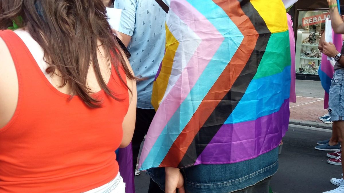 Un joven se cubre con una bandera LGTBIQ+ durante una manifestación.