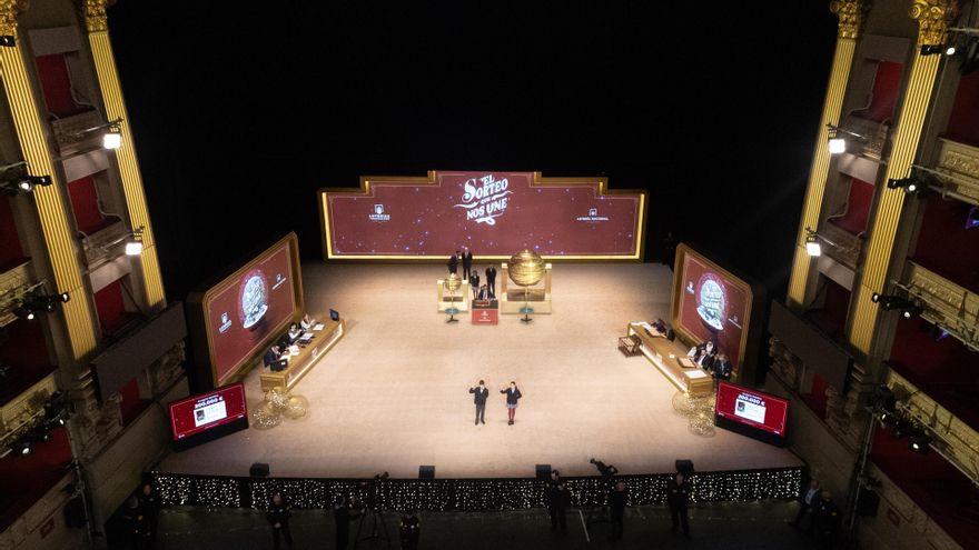 Varias personas ven como los niños del Colegio de San Idefonso cantan los números premiados durante la celebración del Sorteo Extraordinario de la Lotería de Navidad 2025.