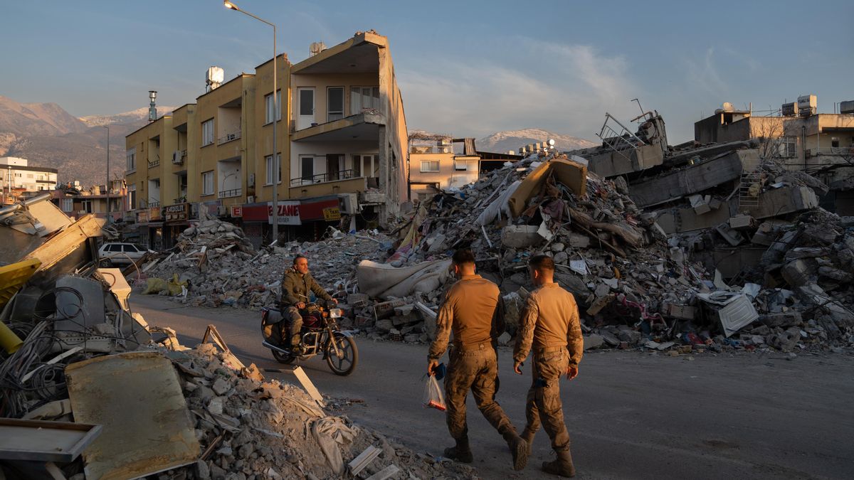 Archivo - Varias personas caminan por los escombros de los edificios derribados por el terremotoen Iskenderun, Turquía.