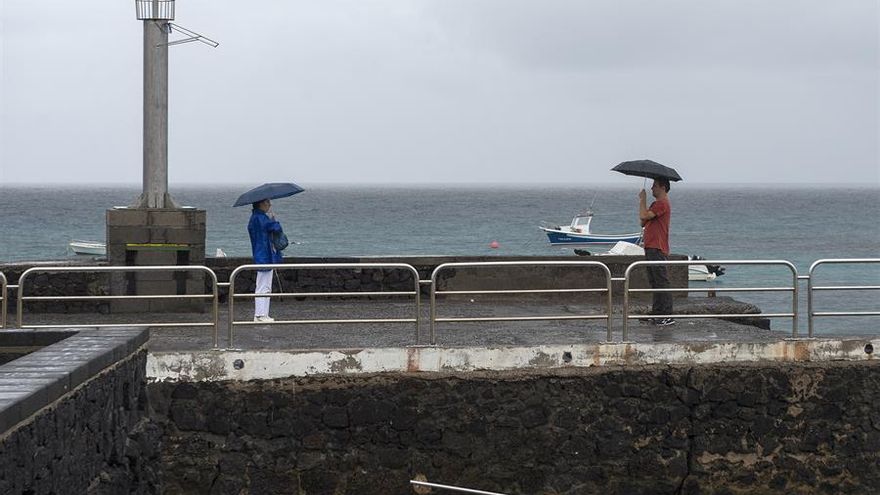 La tormenta tropical Hermine a su paso por Canarias deja lluvias moderadas en la isla de Lanzarote. En la foto unos turistas se fotografían en el muelle de Punta Mujeres (Haría).