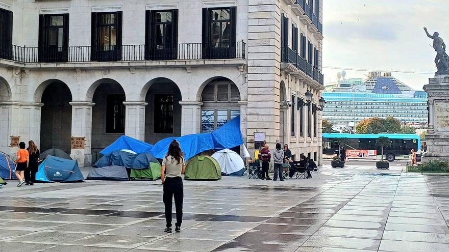 La acampada con el crucero al fondo, atracado en la bahía de Santander.