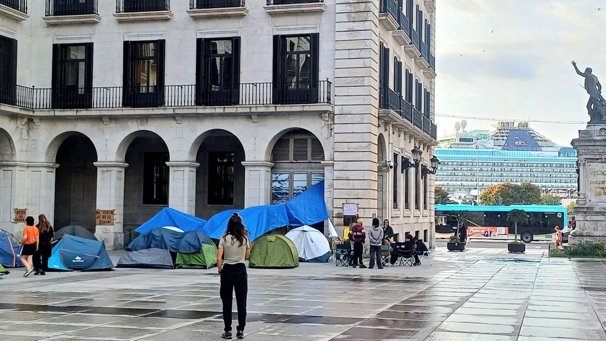 La acampada con el crucero al fondo, atracado en la bahía de Santander.