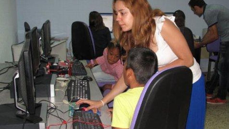 Una monitora del programa atendiendo a niños asistentes al taller