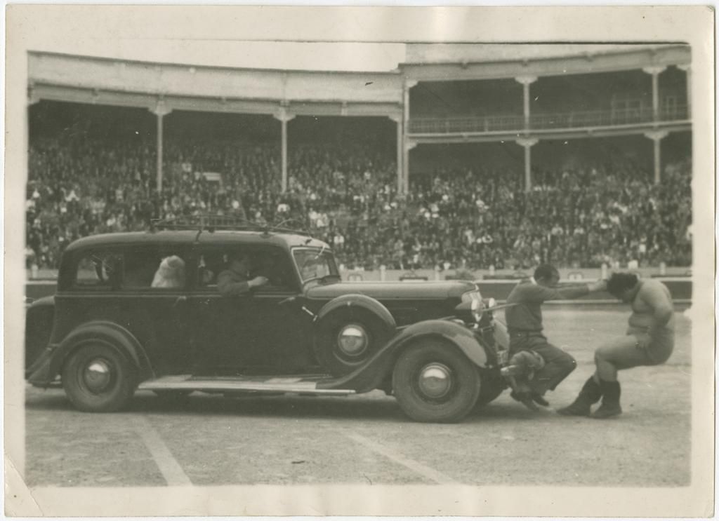 Un forzudo mueve un vehículo en un espectáculo en la plaza de toros en 1955
