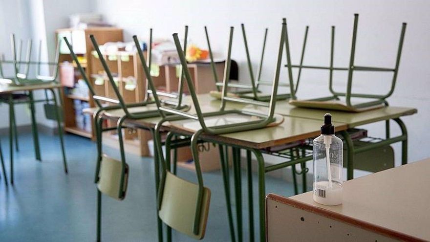 Aula vacía, con un bote de hidrogel en la mesa del docente