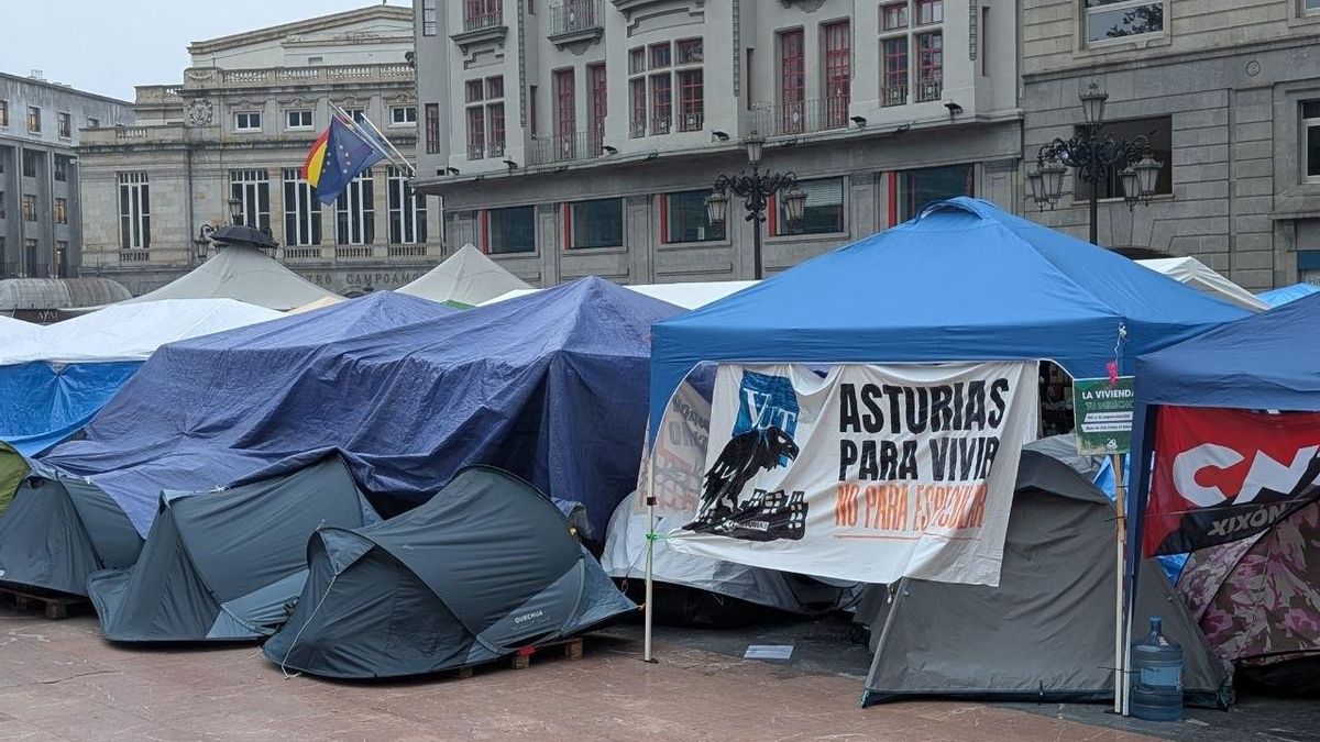 La acampada, en la Plaza de La Escandalera, está acompañada de eslóganes contra el rentismo. Al fondo, el Teatro Campoamor en Oviedo/Uviéu.