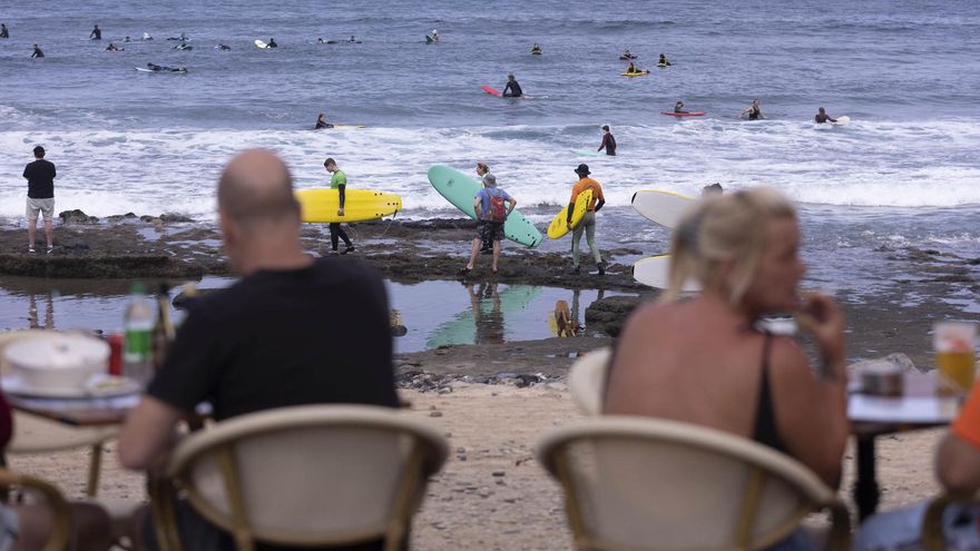 Numerosos turistas disfrutan del buen tiempo este sábado en la zona turística del municipio de Arona, al sur de la isla de Tenerife. En la imagen, surferos cogen olas en la zona de El Conquistador