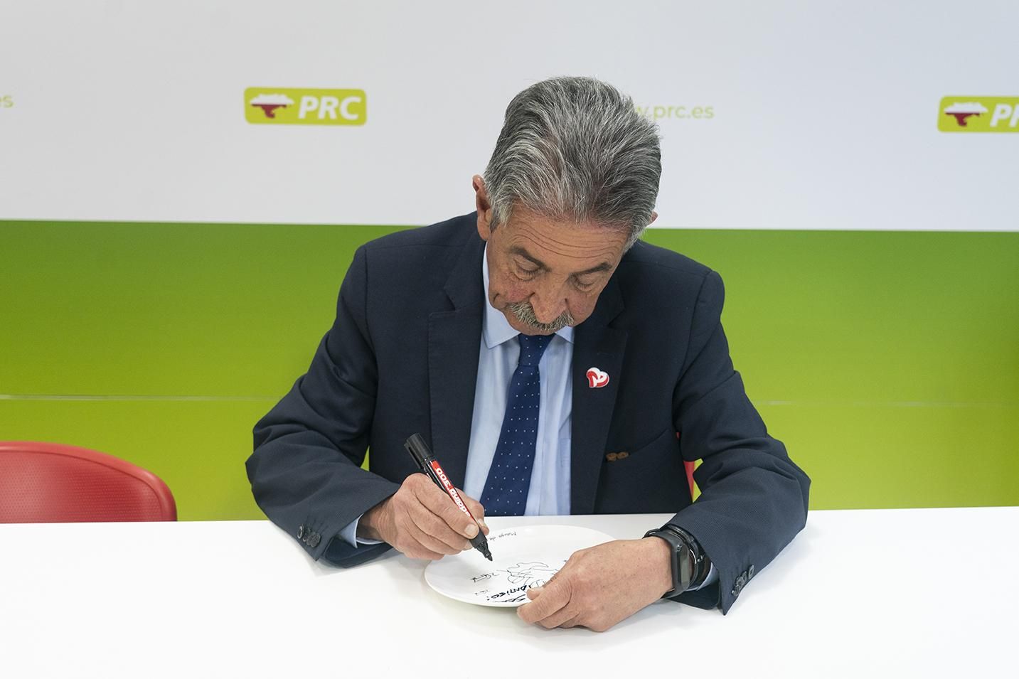 Revilla firma platos con una caricatura suya que reparte en la calle.